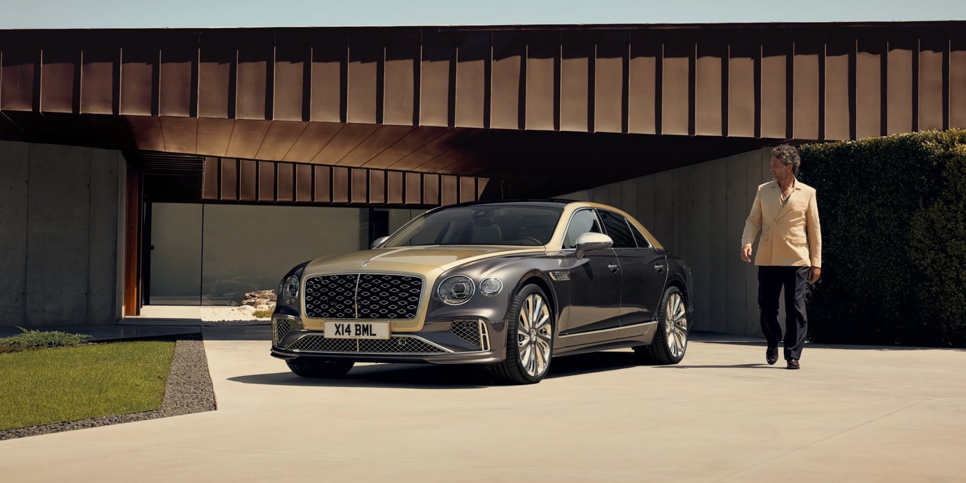 Bentley Santo Domingo Bentley New Flying Spur Mulliner V8 hybrid sedan front three quarters in Rose Gold over Magnetic paint, parked near modern home