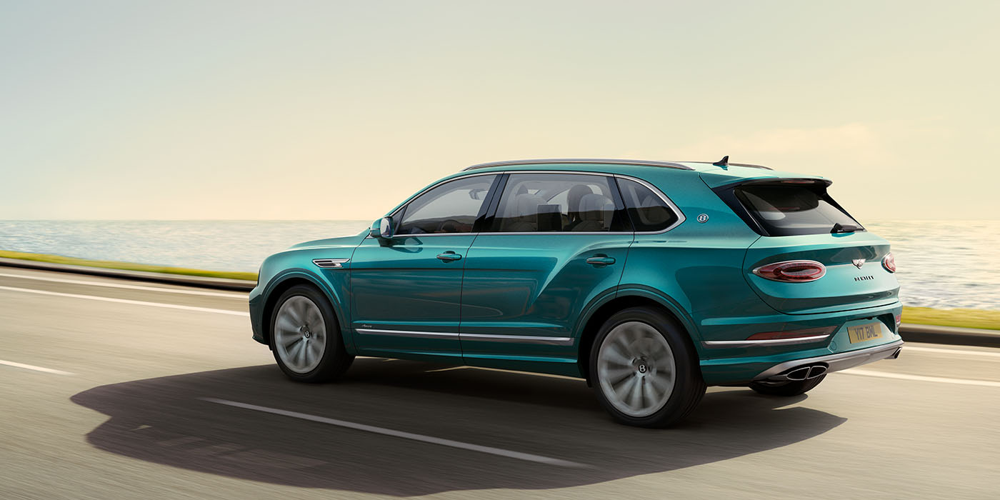Bentley Santo Domingo Bentley Bentayga Extended Wheelbase Azure luxury SUV rear three quarter in Topaz Blue by Mulliner paint, driving on an ocean road.