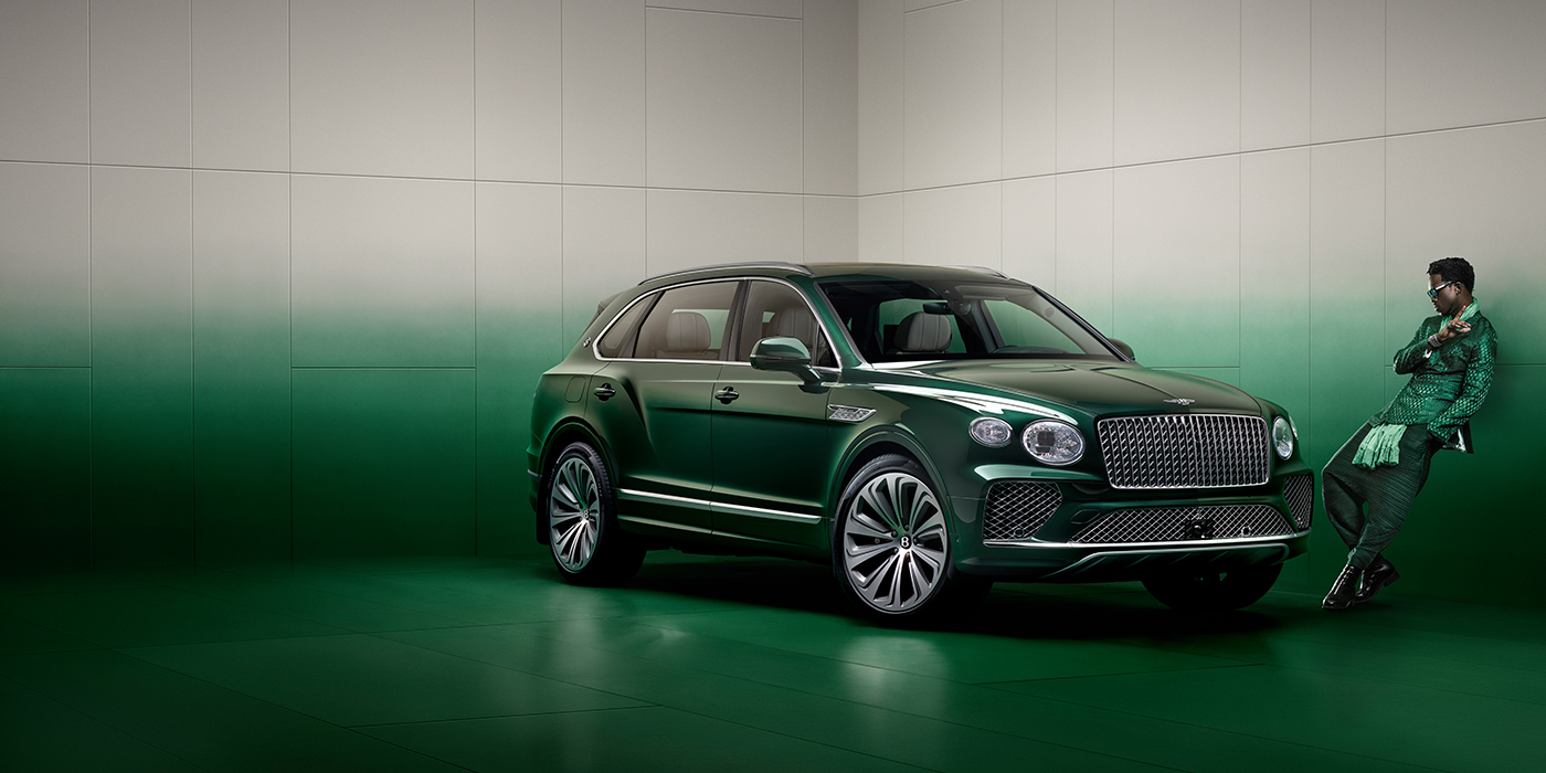 Bentley Santo Domingo Wisdom K leans against wall next to Bentley Bentayga Extended Wheelbase Atelier Edition SUV in Light Emerald green paint