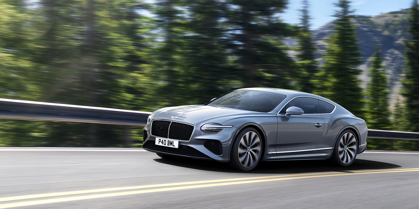 Bentley Santo Domingo New Bentley Continental GT coupe in Silverlake paint and 22 inch ten-spoke wheels, driving dynamically on a tree-lined road in the sunshine