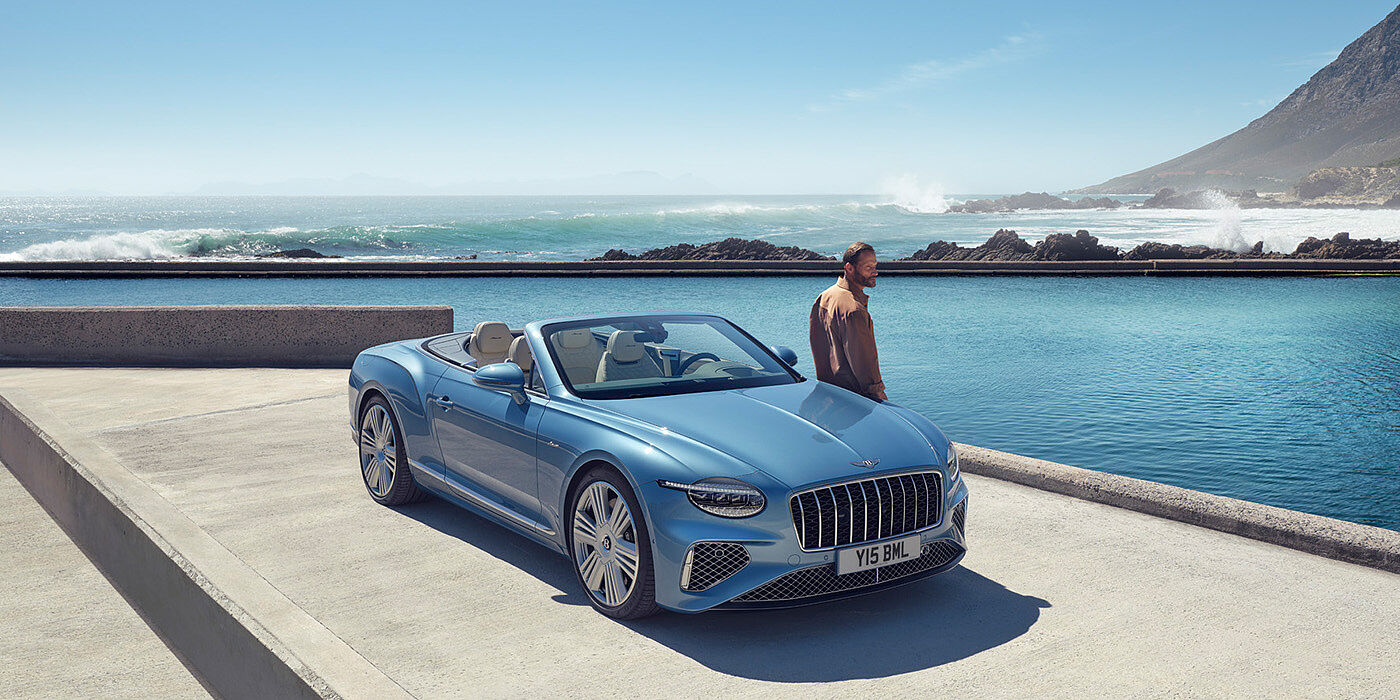 Bentley Santo Domingo New Bentley Continental GTC Azure convertible front view in Light Windsor blue paint with 22 inch ten spoke wheels parked by the sea in the sunshine