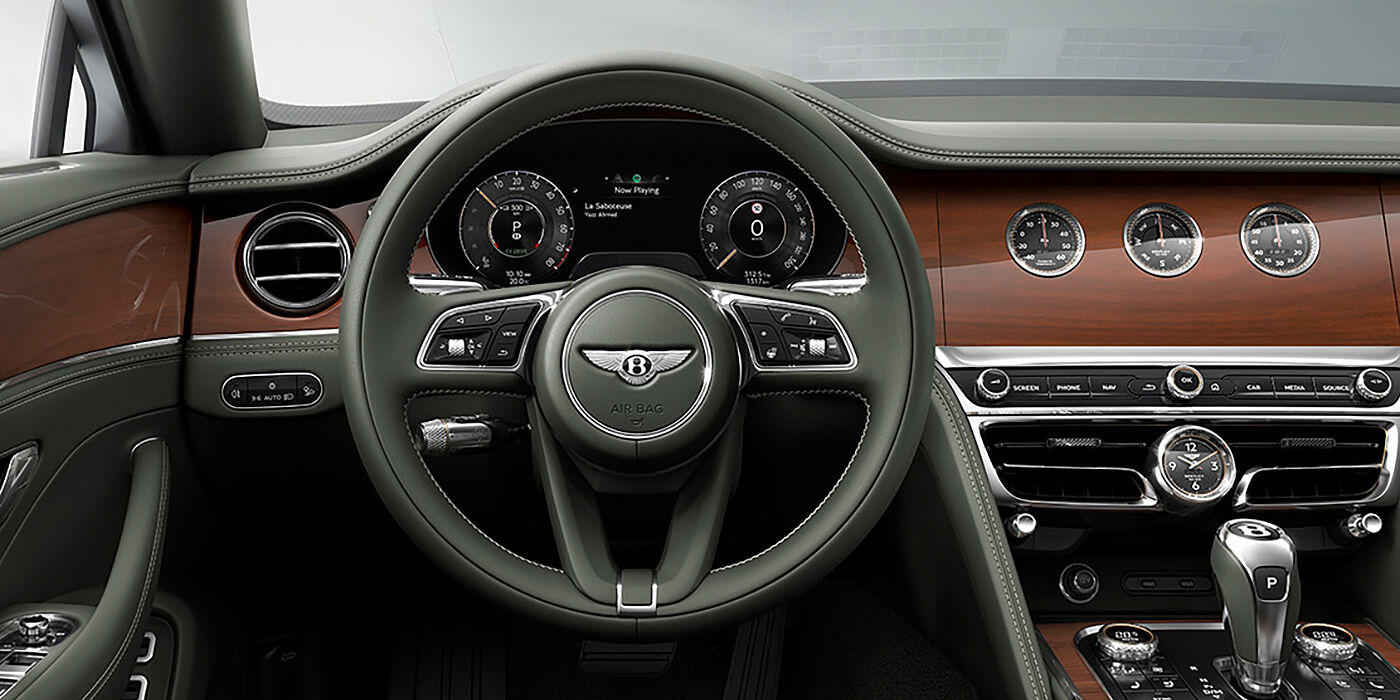 Bentley Santo Domingo New Bentley Flying Spur sedan front cabin in Cumbrian Green hide and Crown Cut walnut veneer showing steering wheel and Rotating Display with three clocks on face