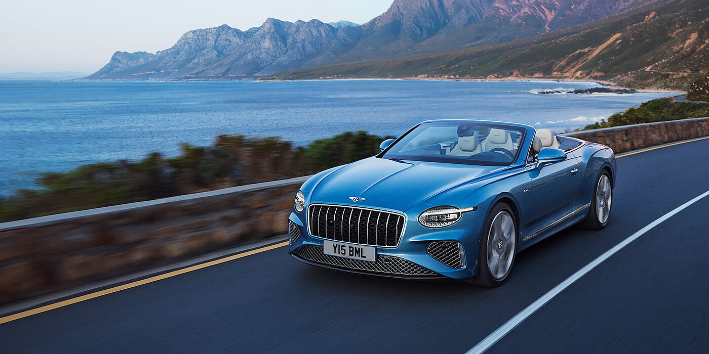 Bentley Santo Domingo New Bentley Continental GTC Azure convertible in Light Windsor blue paint with 22 inch Azure wheels and chrome grill, driving dynamically by the sea