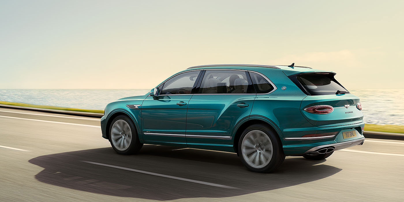Bentley Santo Domingo Bentley Bentayga Extended Wheelbase Azure luxury SUV rear three quarter in Topaz Blue by Mulliner paint, driving on an ocean road.