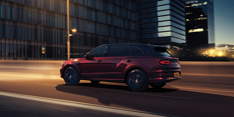 Bentley Santo Domingo Bentley Bentayga Extended Wheelbase Mulliner SUV in Cricket Ball red paint driving dynamically in city at night